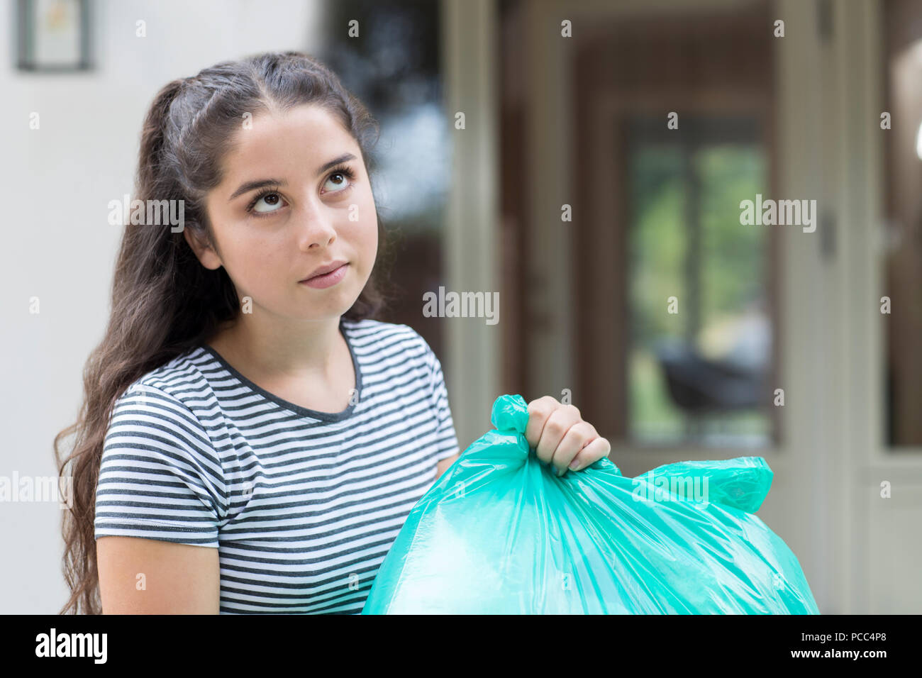 Fed Up Teenage Girl Taking Out Rubbish At Home Stock Photo