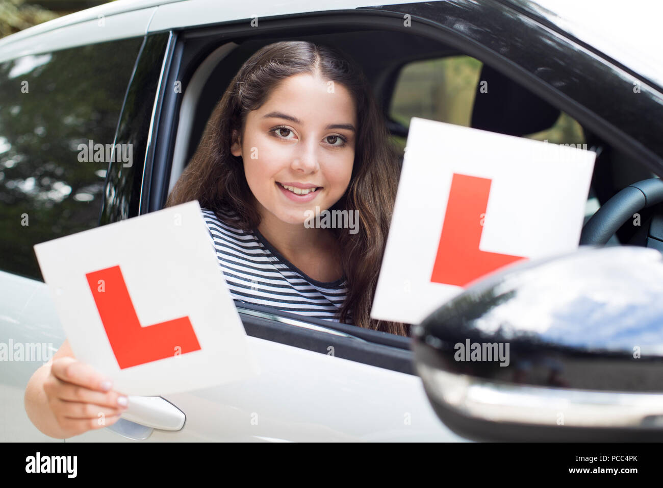 Portrait Of Teenage Girl Passing Driving Exam Holding Learner Plates Stock Photo