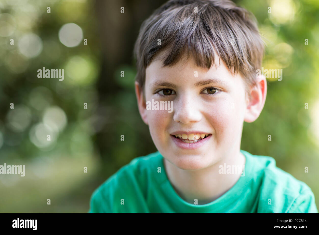 Portrait Of Happy Young Boy Sitting Outdoors Stock Photo