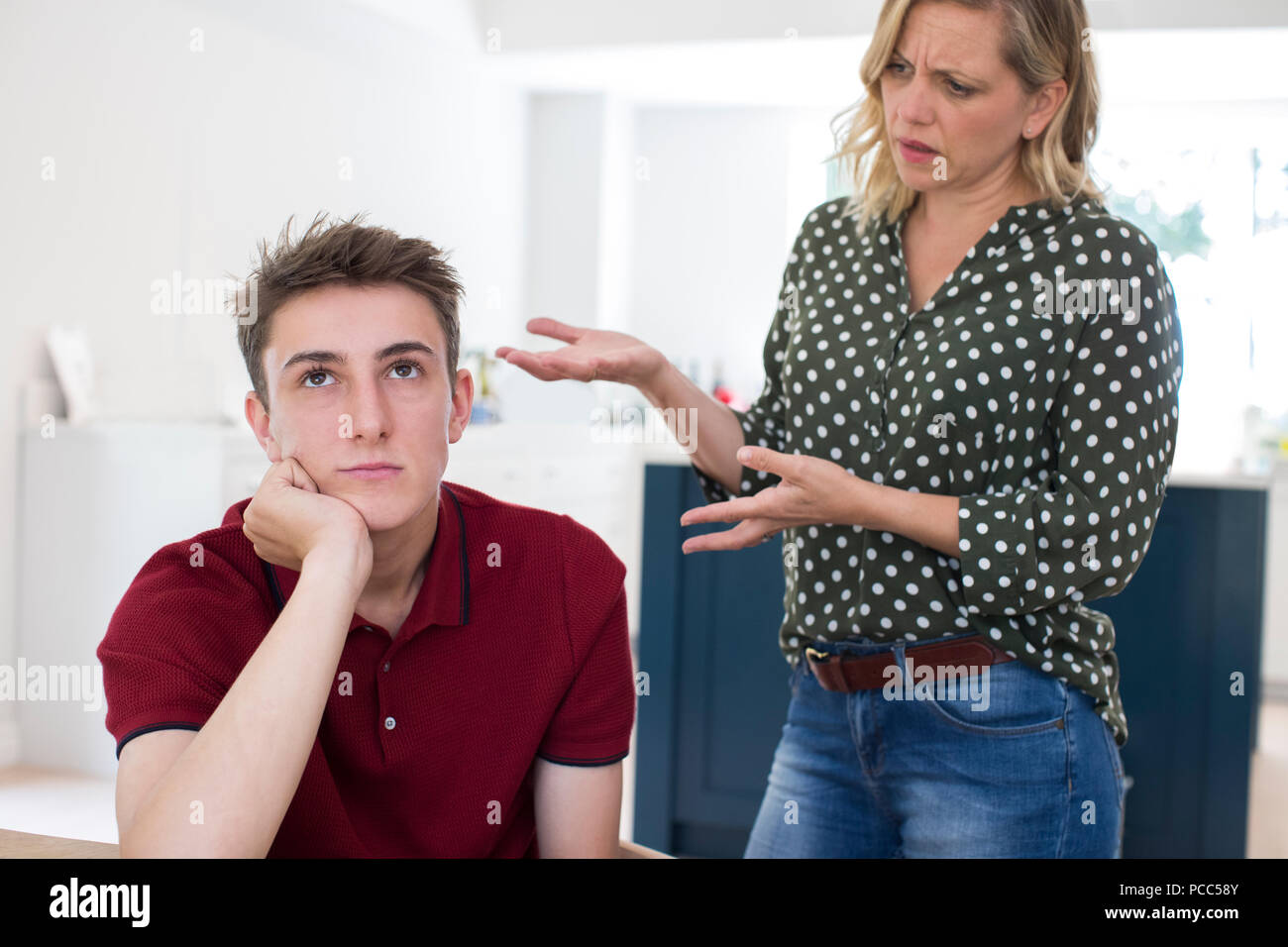 Fed Up Teenage Boy Being Nagged By Mother At Home Stock Photo