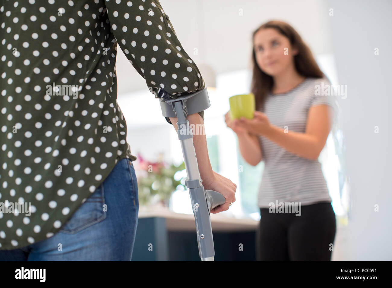 Teenage Daughter Making Drink For Disabled Parent Stock Photo