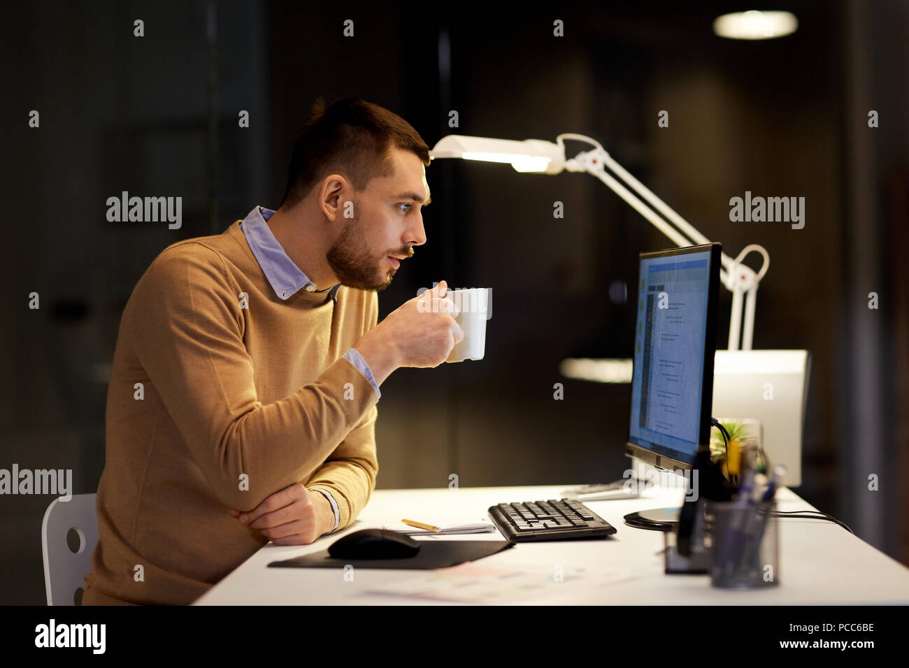 man drinking coffee and working on code at office Stock Photo