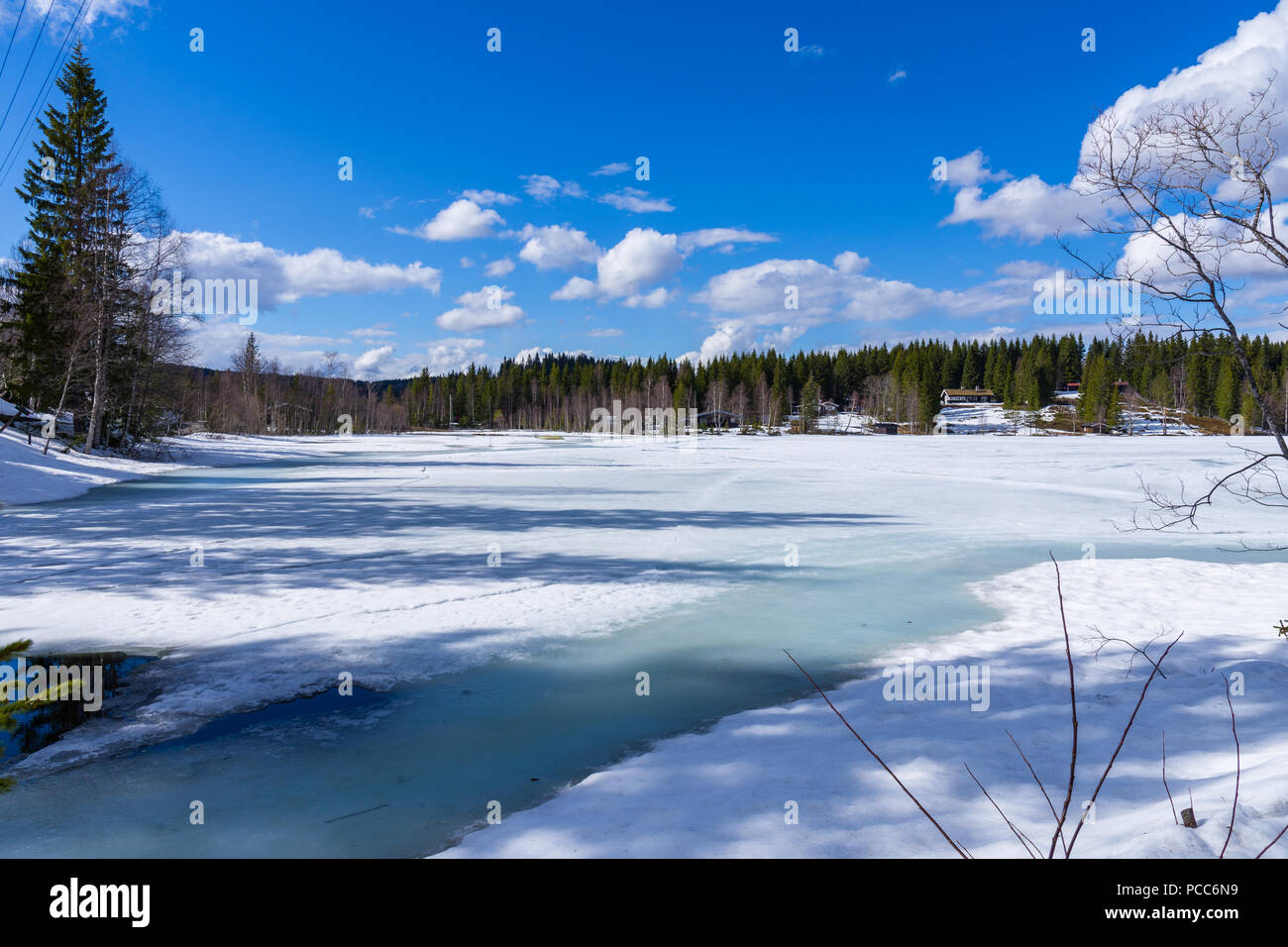 Small houses in the snowy forest overlooking the frozen lake. Norway Stock Photo
