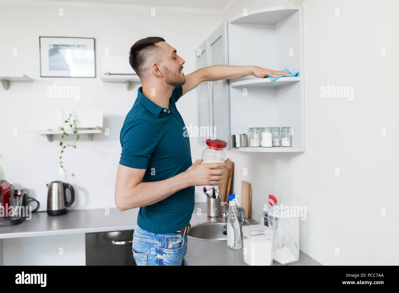 man with rag cleaning kitchen cupboard at home Stock Photo