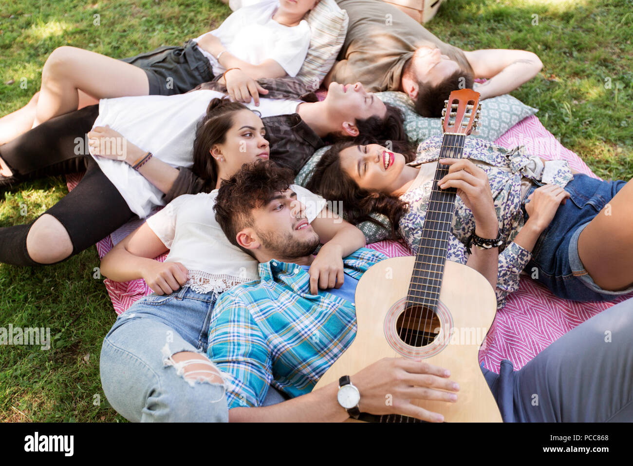 friends with guitar chilling on picnic blanket Stock Photo - Alamy