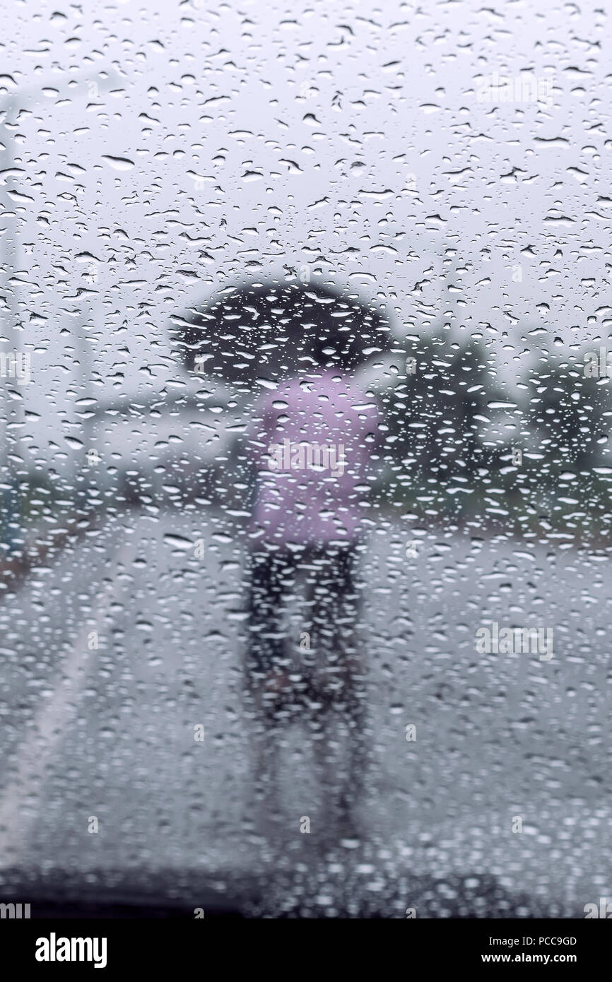 Raindrops falling on glass, abstract blurs - monsoon stock image . Stock Photo