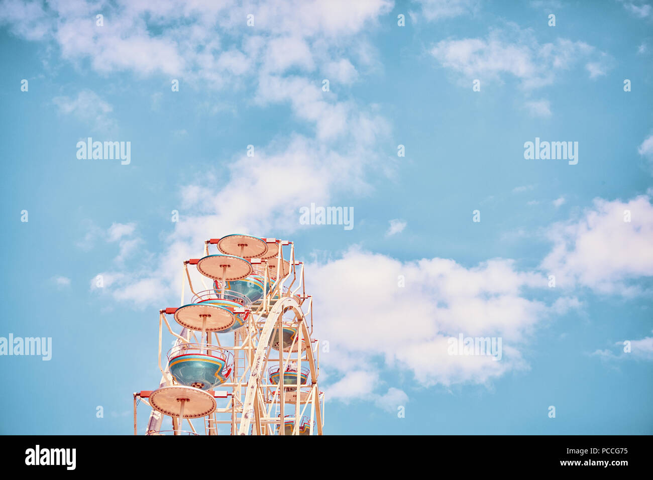 Retro stylized picture of a Ferris wheel against sky, space for text. Stock Photo
