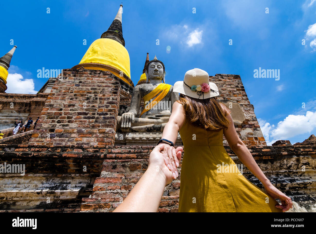 Portrait of Beautiful Asian girl leading her partner by hand to the famous Wat Yai Chai Mongkol. The wat is a Buddhist temple in Ayutthaya, Thailand. Stock Photo