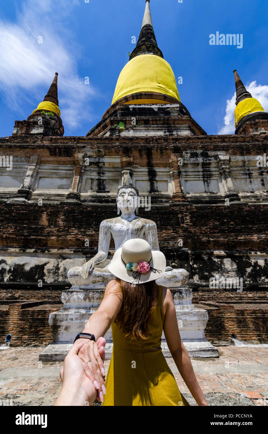 Portrait of Beautiful Asian girl leading her partner by hand to the famous Wat Yai Chai Mongkol. The wat is a Buddhist temple in Ayutthaya, Thailand. Stock Photo
