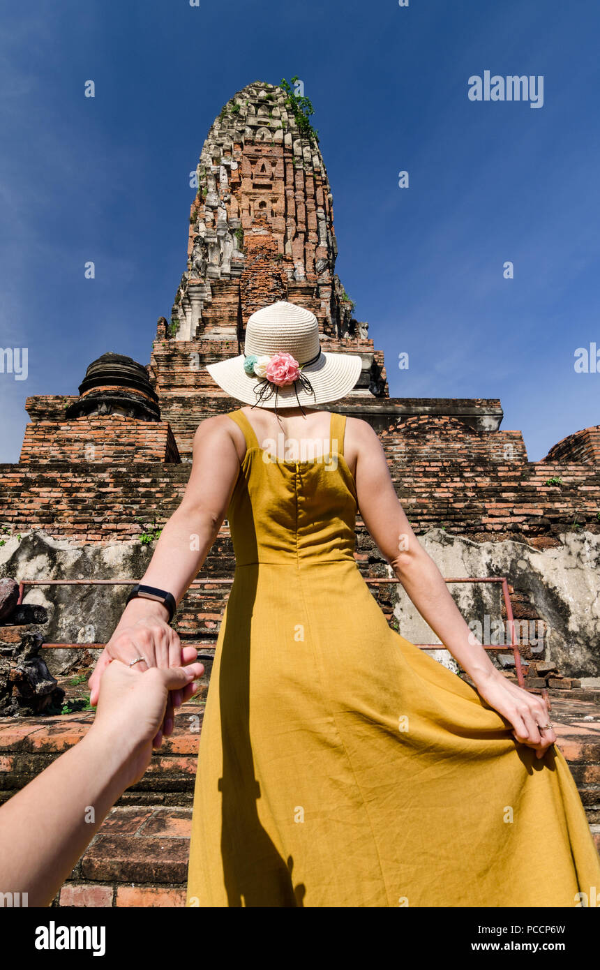 Portrait of Beautiful Asian girl leading her partner by hand to the famous Wat Phra Ram. The Wat is a Buddhist temple in Ayutthaya, Thailand. Stock Photo