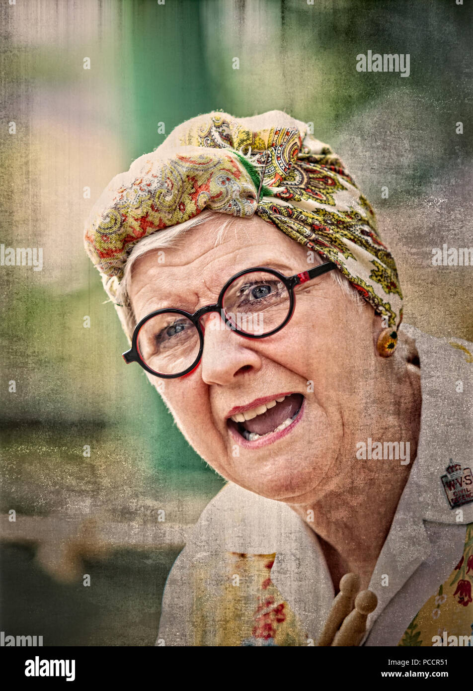 Close-up, front view portrait of woman in headscarf & overall as authentic vintage housewife, charlady at UK 1940's WWII summer event. Stock Photo