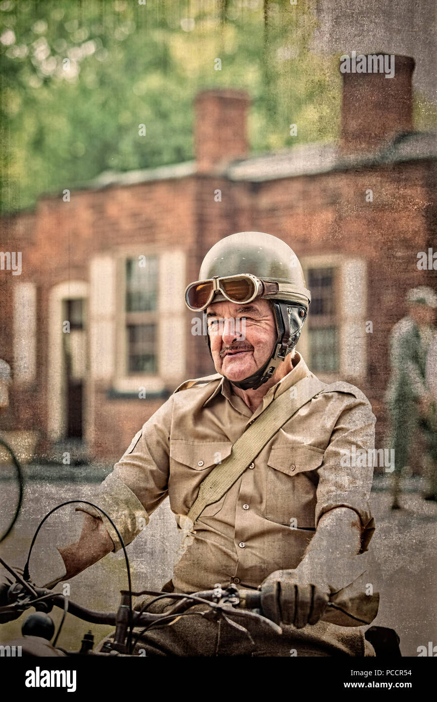 Close up isolated senior man in 1940s military costume as war dispatch rider on vintage motorcycle, Black Country Museum 1940s WW2 summer event, UK. Stock Photo
