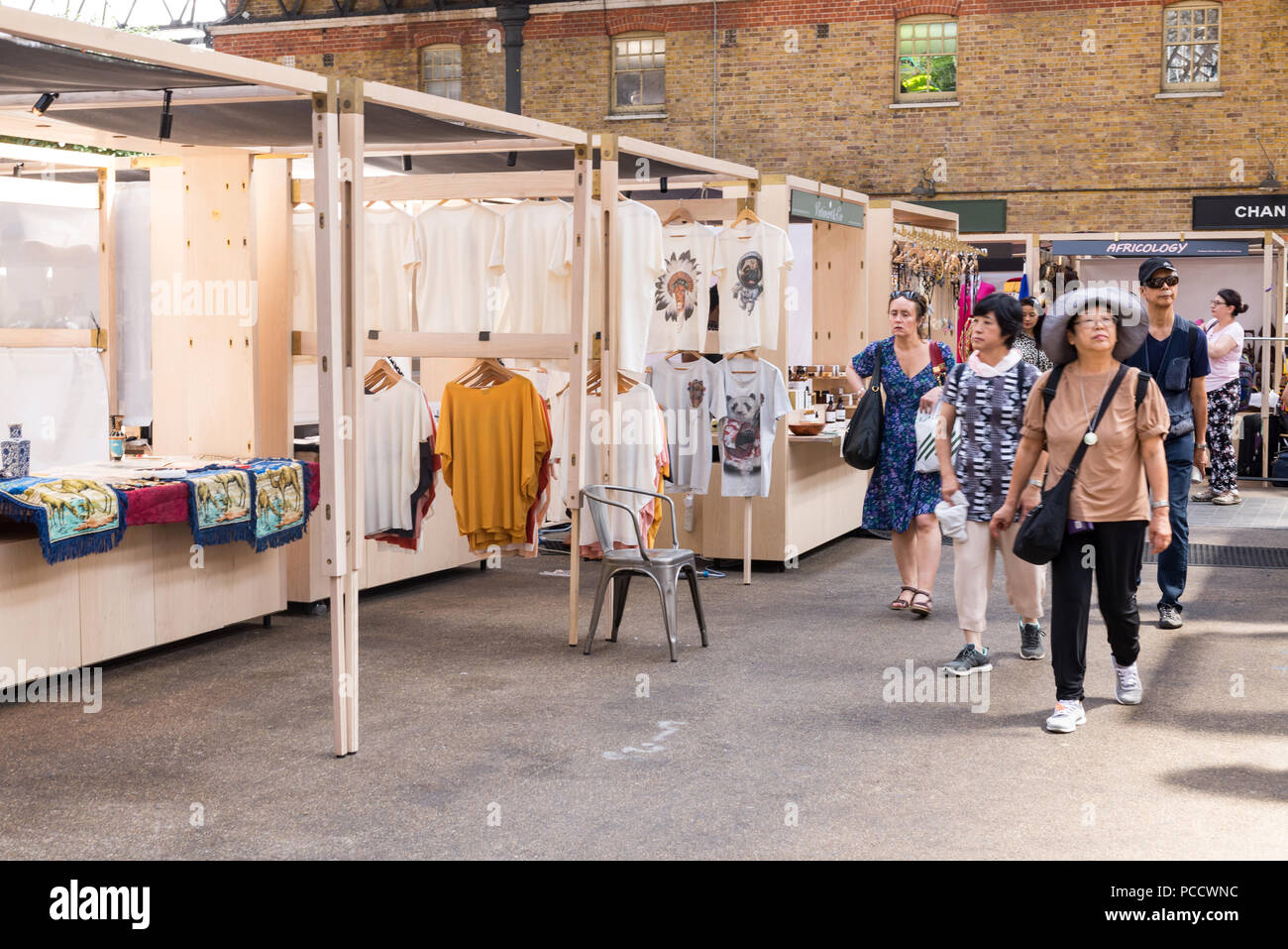 People shopping and walking around the stalls in Old Spitalfields indoor market. Spitalfields, East London, UK Stock Photo