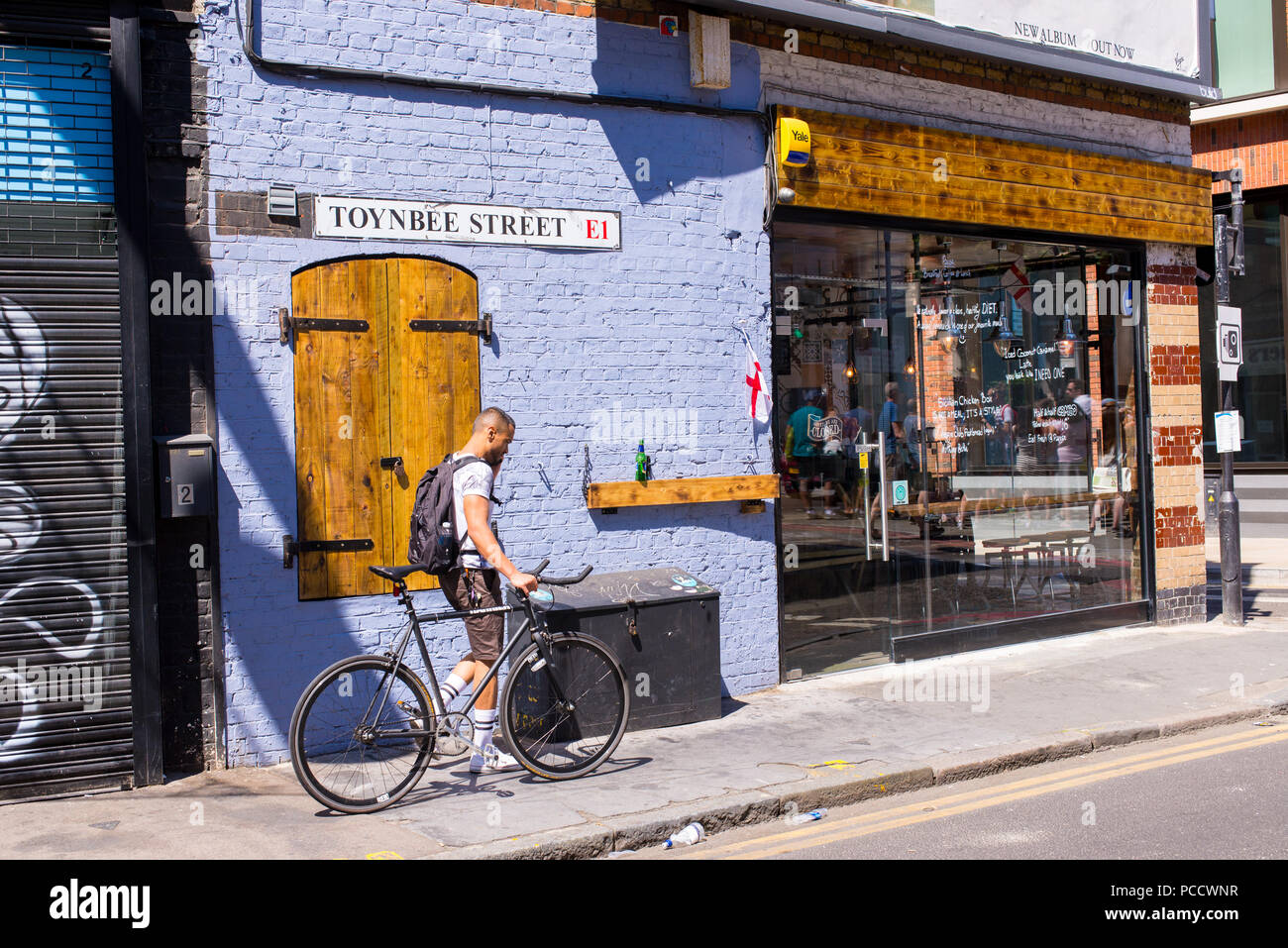 Hipster young man walking pushing his fixed gear bike in Spitalfield, East London, UK Stock Photo
