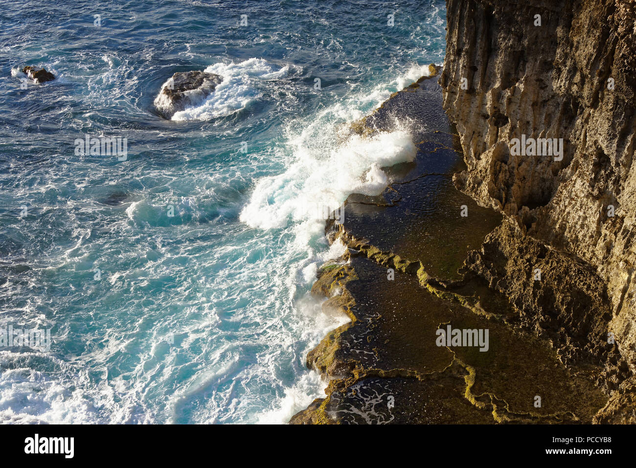 Sea crashing onto rocks at base of cliff Stock Photo