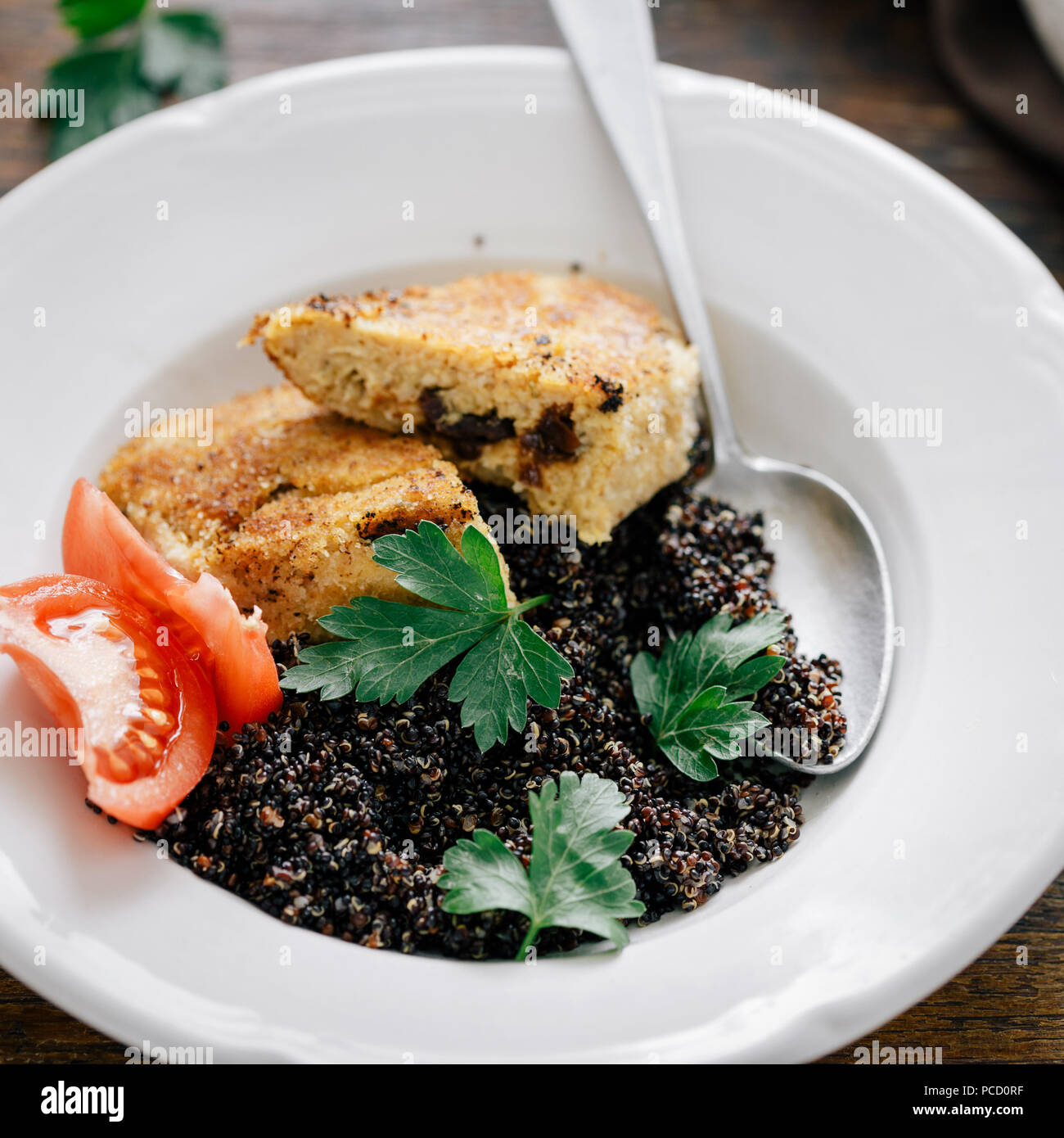 Close up plate with black quinoa and oatmeal cutlets with prunes on wooden table. Vegetarian dinner table Stock Photo