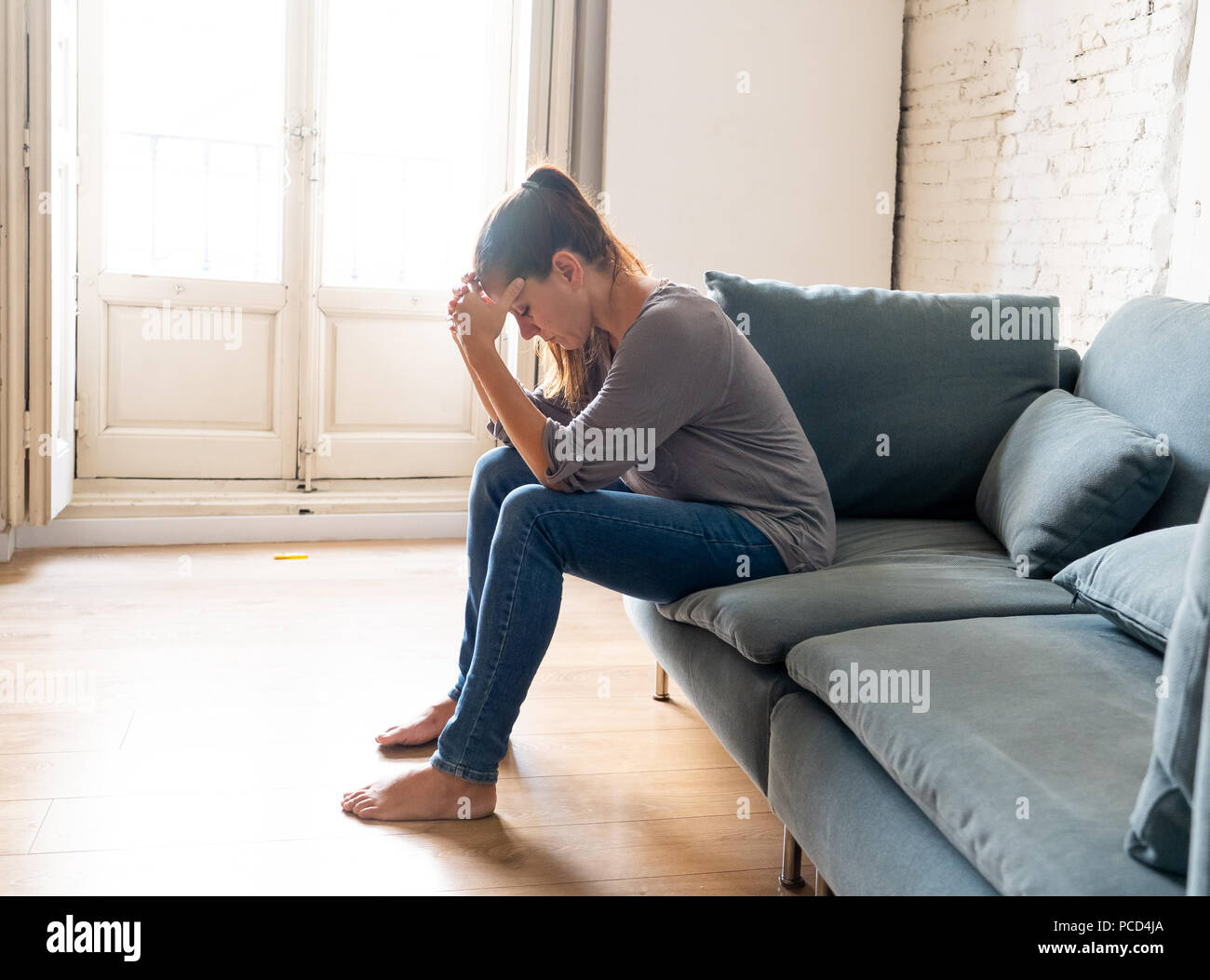 Young attractive latin woman lying at home living room couch feeling sad tired and worried suffering depression in mental health, problems and broken  Stock Photo