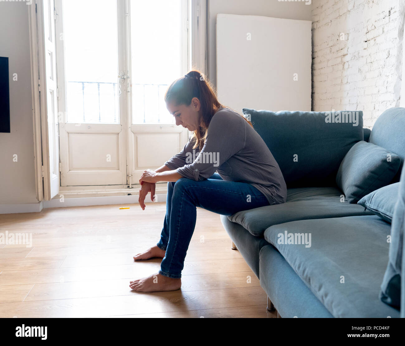 Young attractive latin woman lying at home living room couch feeling sad tired and worried suffering depression in mental health, problems and broken  Stock Photo