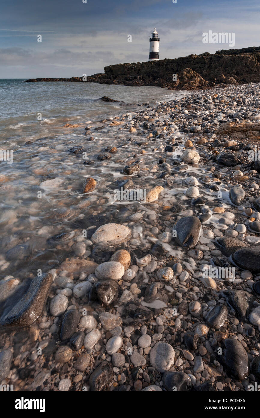 Lighthouse at Penmon Point, Anglesey, North Wales with a pebble beach Stock Photo