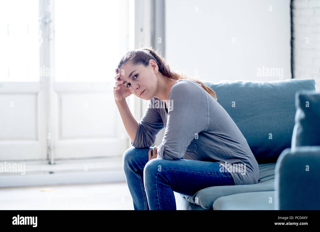 Young attractive latin woman lying at home living room couch feeling sad tired and worried suffering depression in mental health, problems and broken  Stock Photo