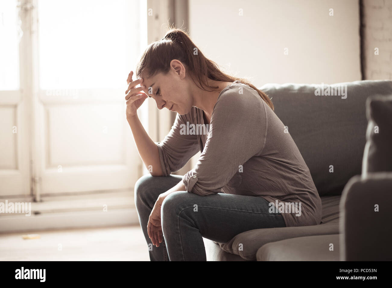 Young attractive latin woman lying at home living room couch feeling sad tired and worried suffering depression in mental health, problems and broken  Stock Photo