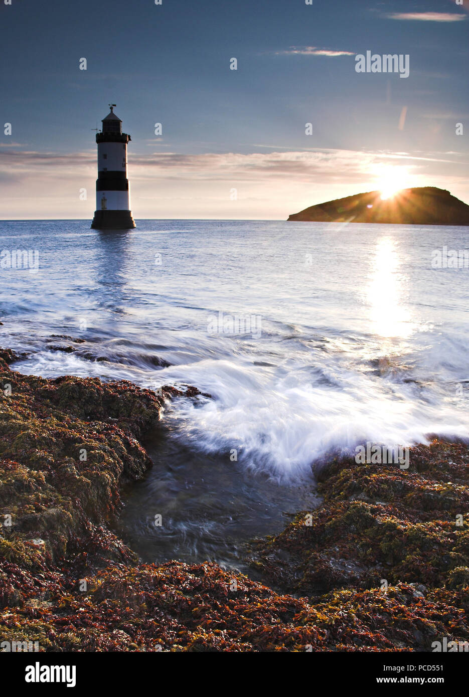 Lighthouse at Penmon Point at sunrise, Anglesey, North Wales, with Puffin Island in the background Stock Photo