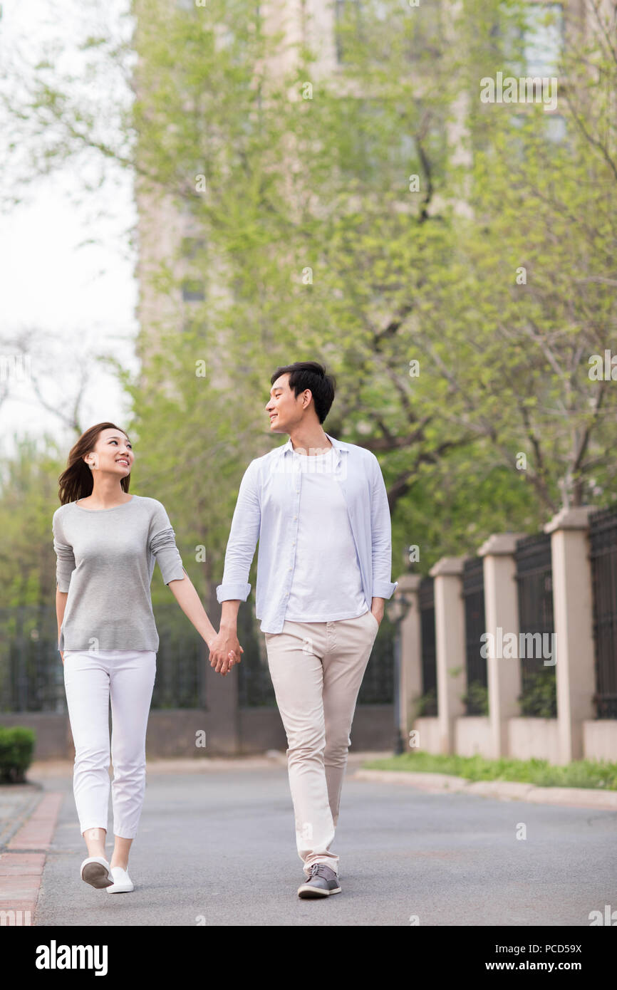 Happy young Chinese couple holding hands walking Stock Photo - Alamy