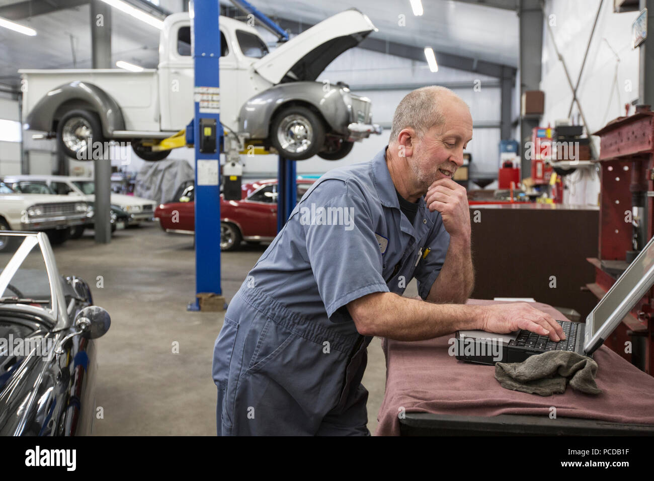 A senior caucasian male car mechanic working on his laptop computer in his  classic car repair shop Stock Photo - Alamy