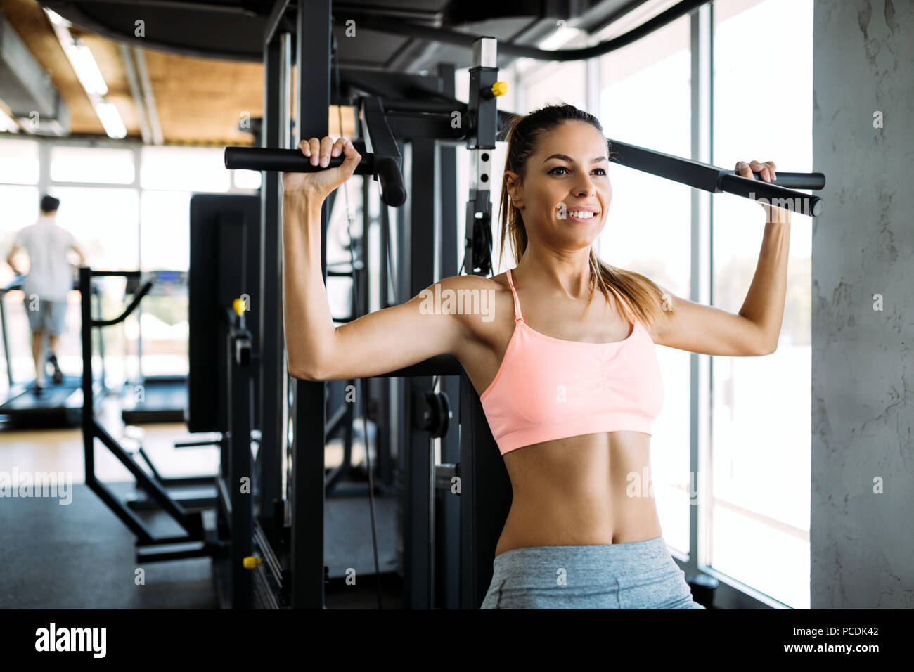 Happy woman exercising on a shoulder press in fitness center Stock Photo