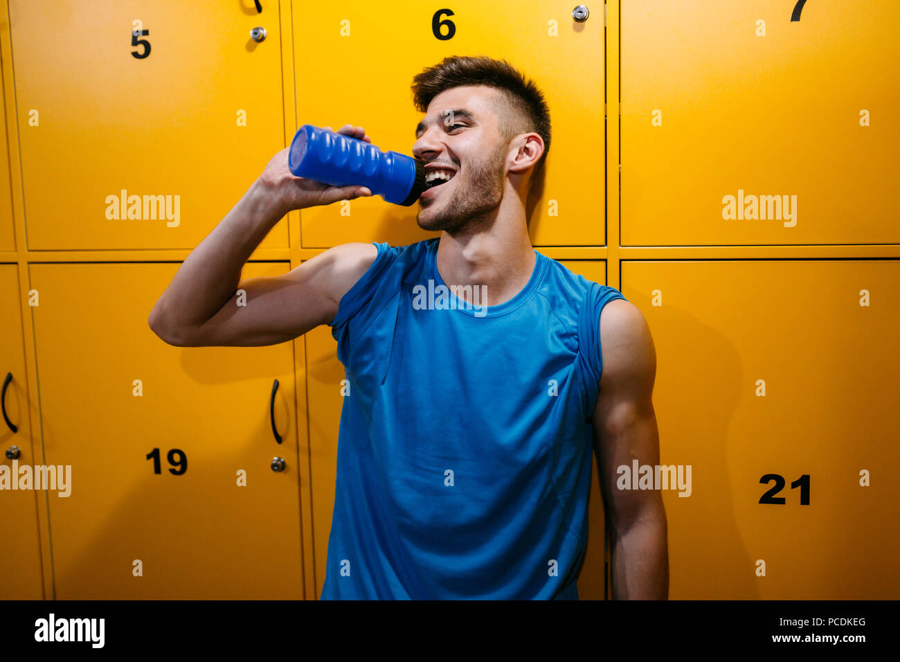 Handsome man drinking water in locker room Stock Photo