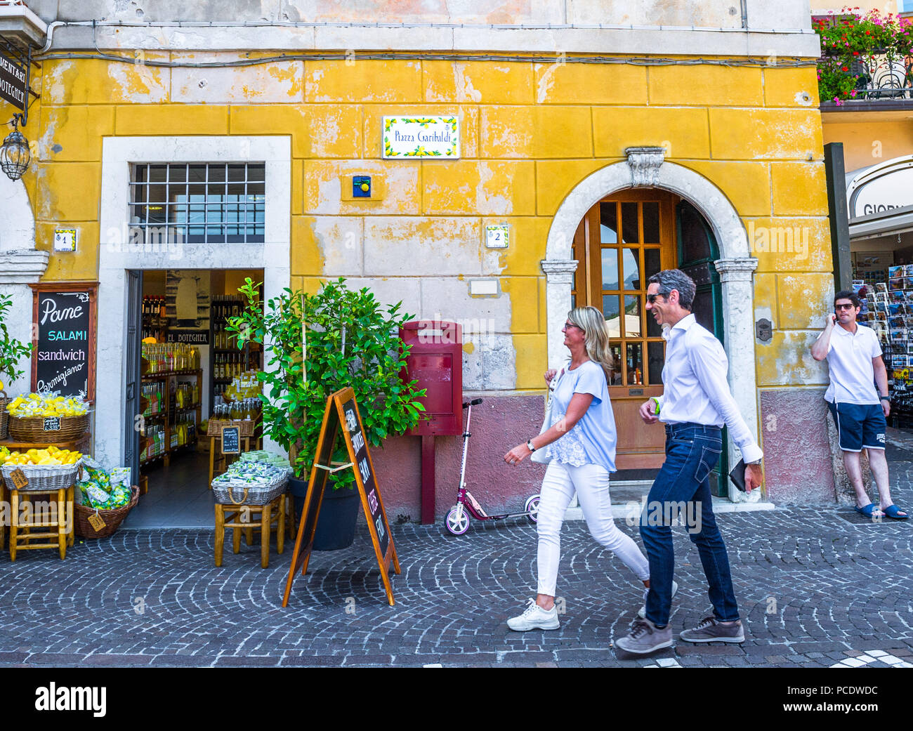 Man and woman walking down a cobble street in Limone, Italy. Stock Photo