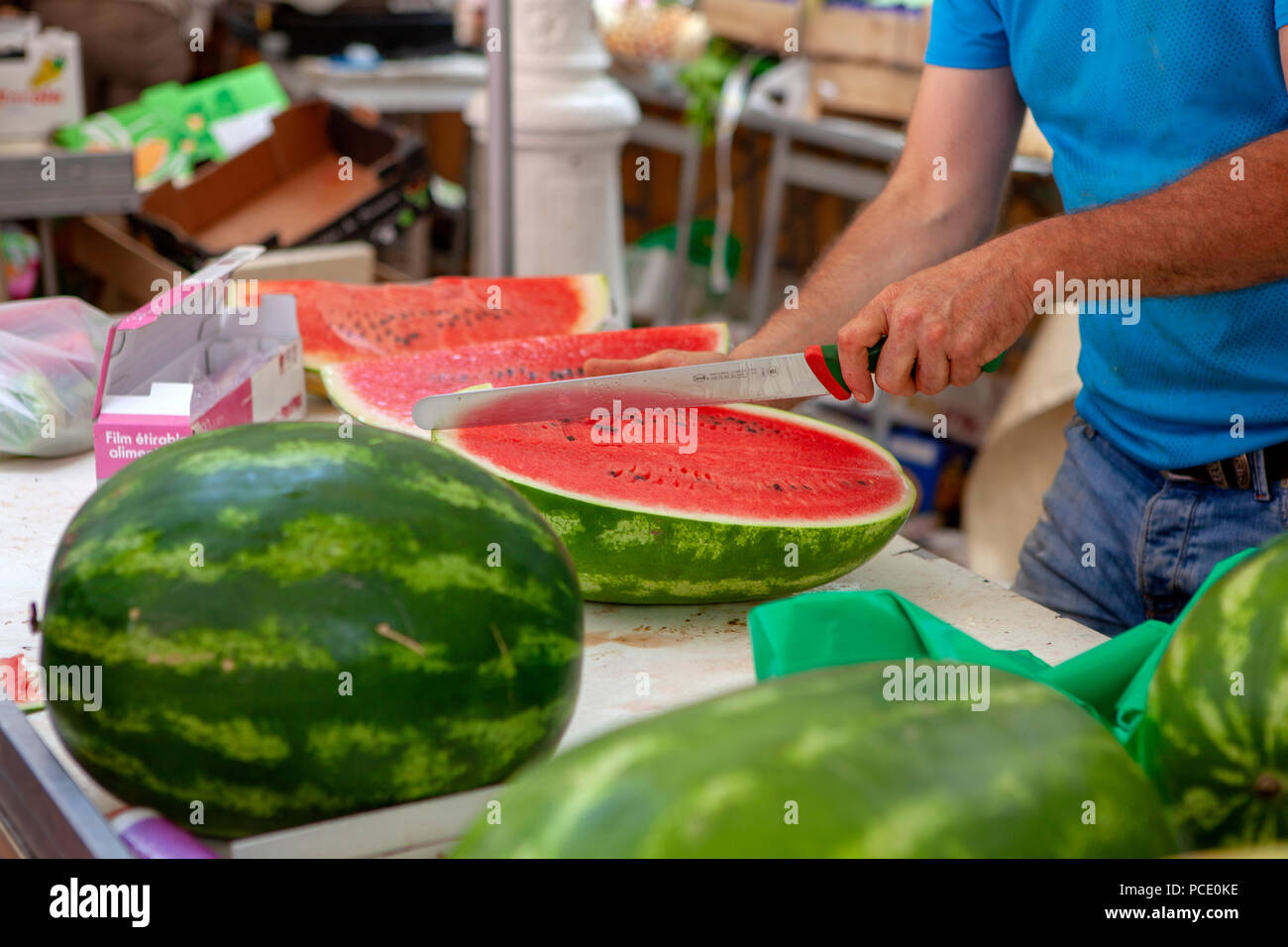 Fruit seller cutting and slicing water melon and putting for sale on a French market stall in Toulon southern France Stock Photo