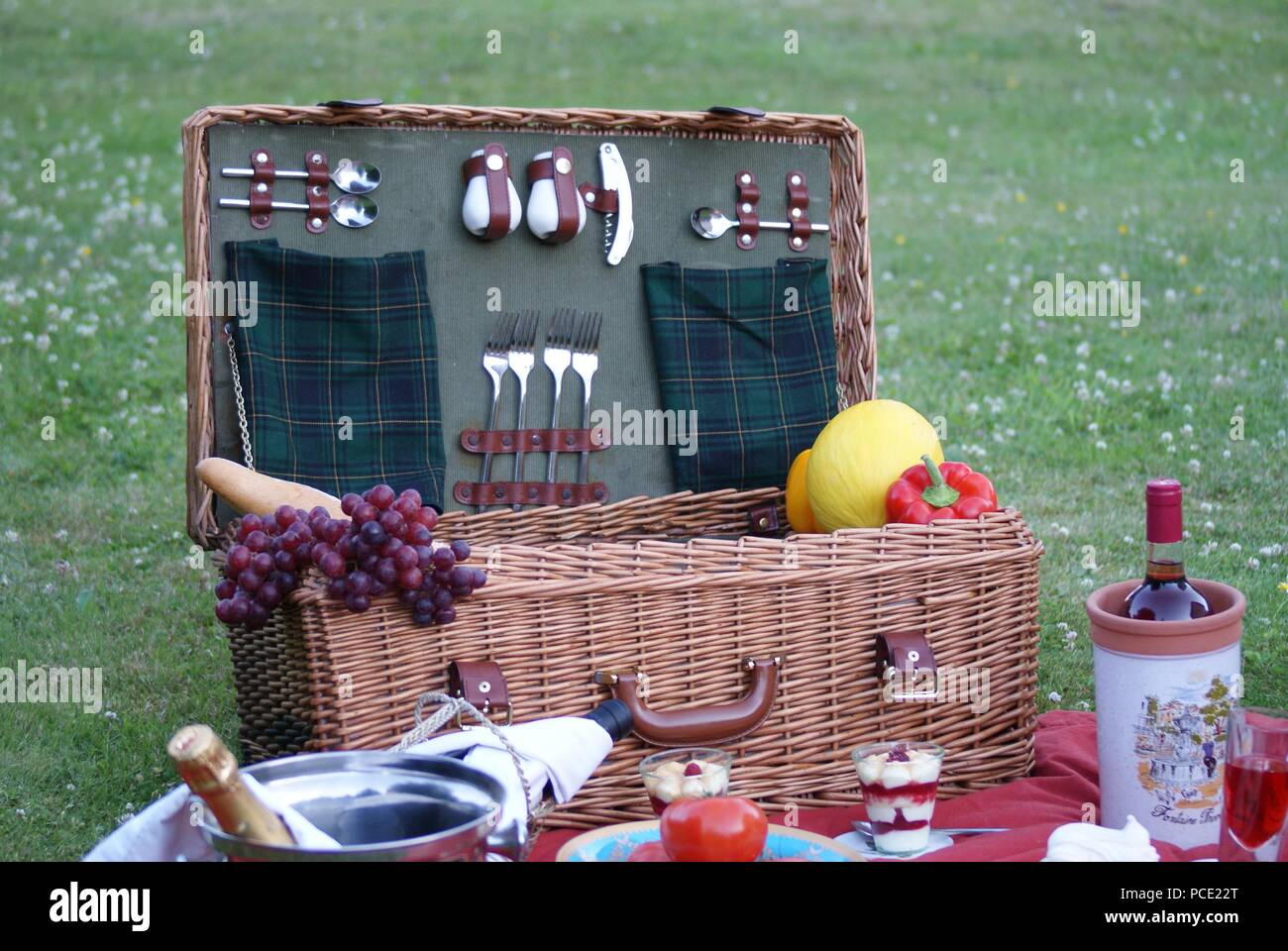 a picnic basket on the green meadow with delicacies and organic food Stock Photo