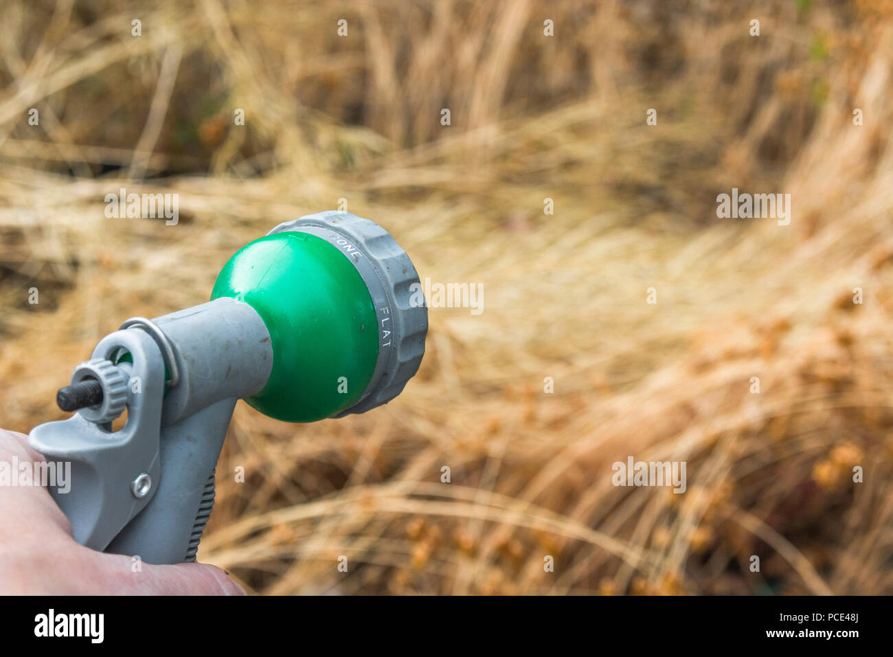 Garden hosepipe spray gun - as metaphor for 2018 heatwave and UK drought, and hosepipe ban. [Photographer's hand in shot - use without MR form]. Stock Photo