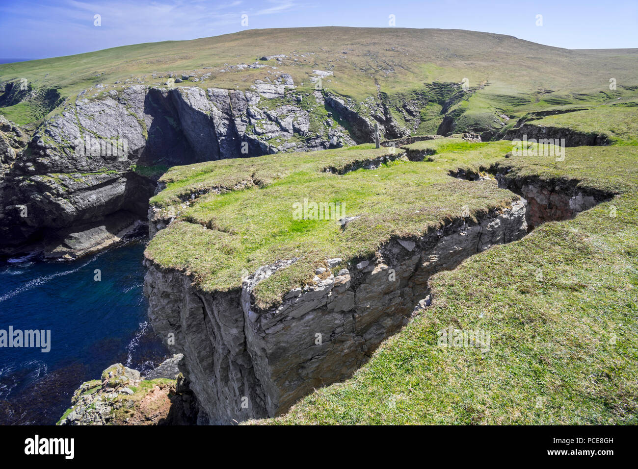 Coastal erosion showing huge cracks / clefts in the rock on top of eroded sea cliff, Shetland