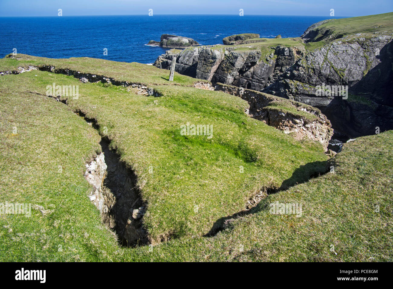 Coastal erosion showing huge cracks / clefts in the rock on top of eroded sea cliff, Shetland
