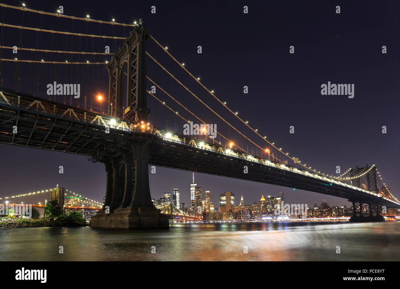 Panorama of  Manhattan and Brooklyn bridges and New York City with lights and reflections at night, USA Stock Photo