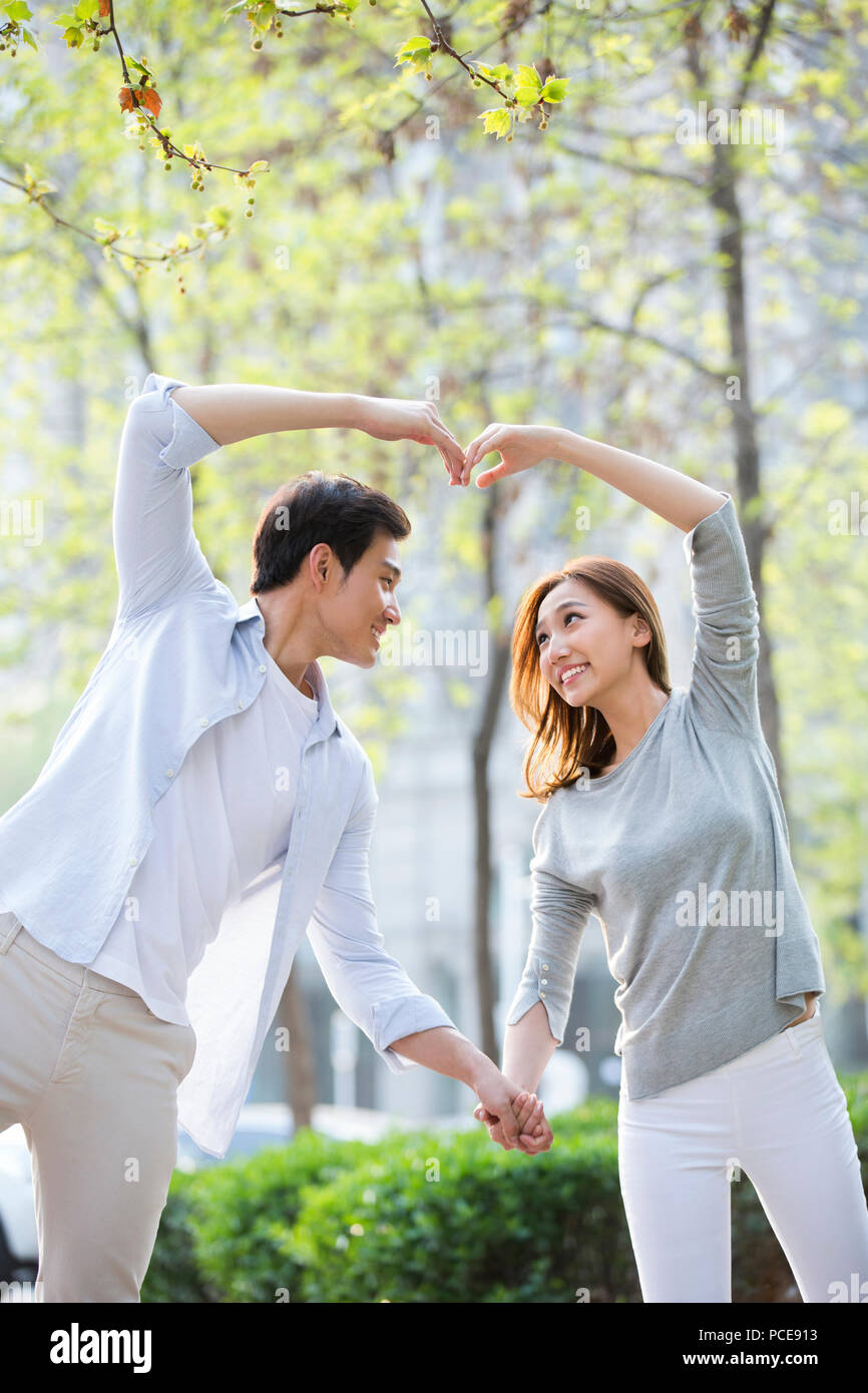 Happy young Chinese couple doing heart shape gesture Stock Photo - Alamy