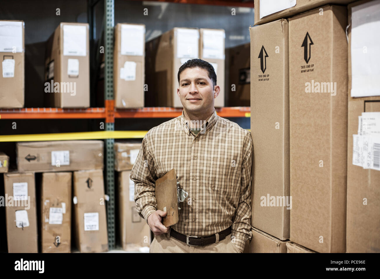 Hispanic Rack A hispanic male warehouse worker standing next to racks of boxed ...