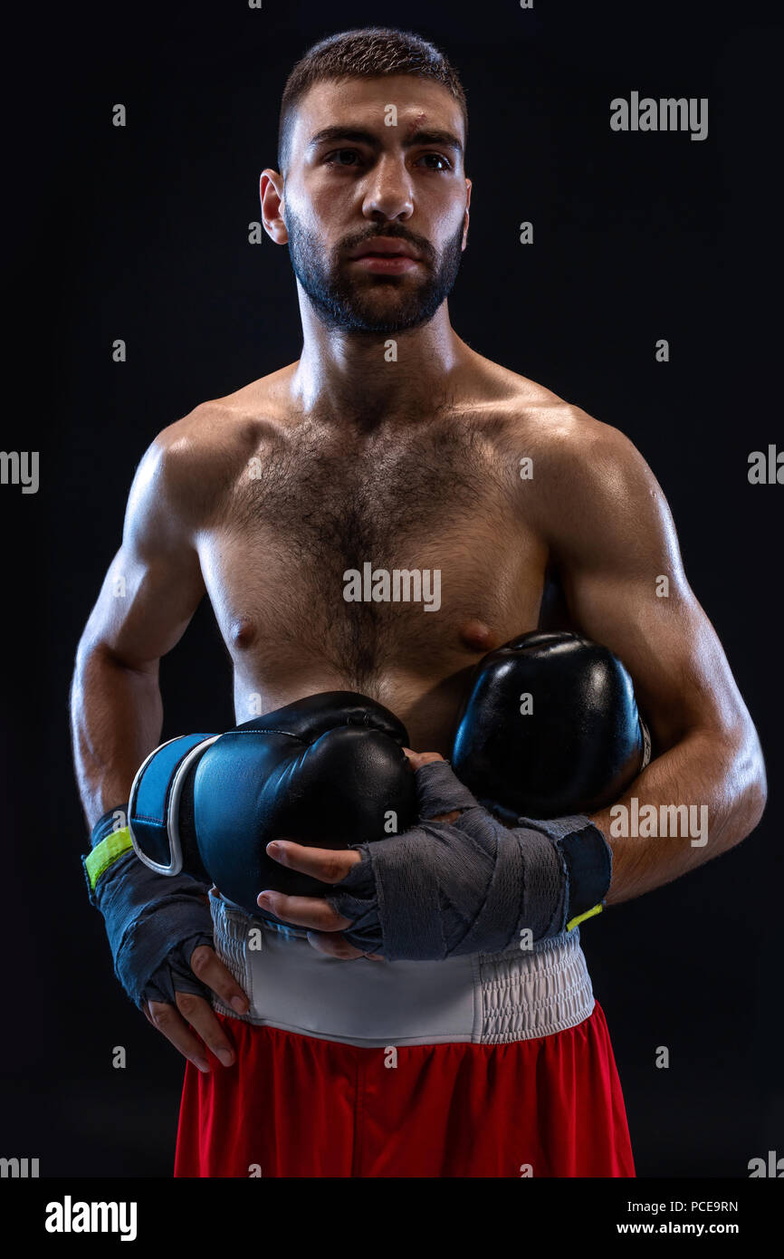 Man's hands in boxing bandages holds boxing gloves on a black background. Stock Photo