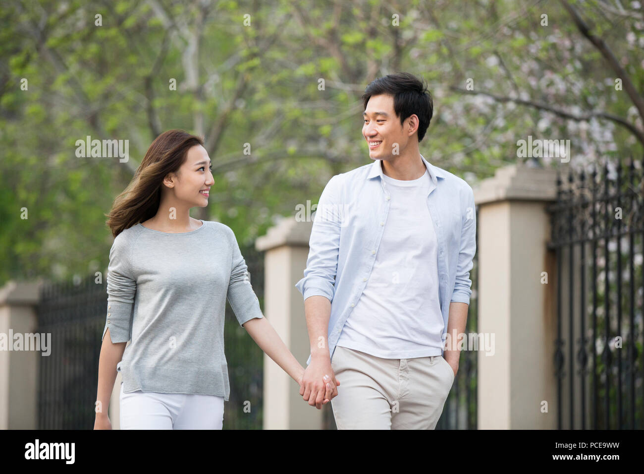 Happy young Chinese couple holding hands walking Stock Photo