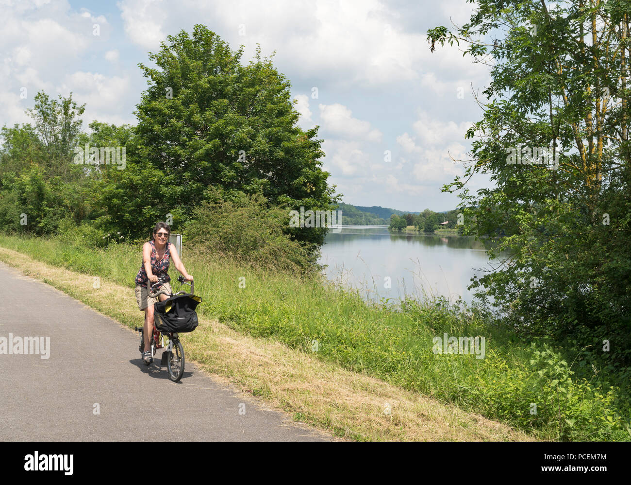 Mature woman cyclist on the La Boucle de la Moselle bike path alongside the Moselle river, France, Europe Stock Photo