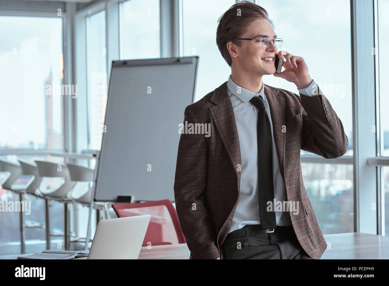 Young businessman in eyeglasses at office standing looking out t Stock Photo