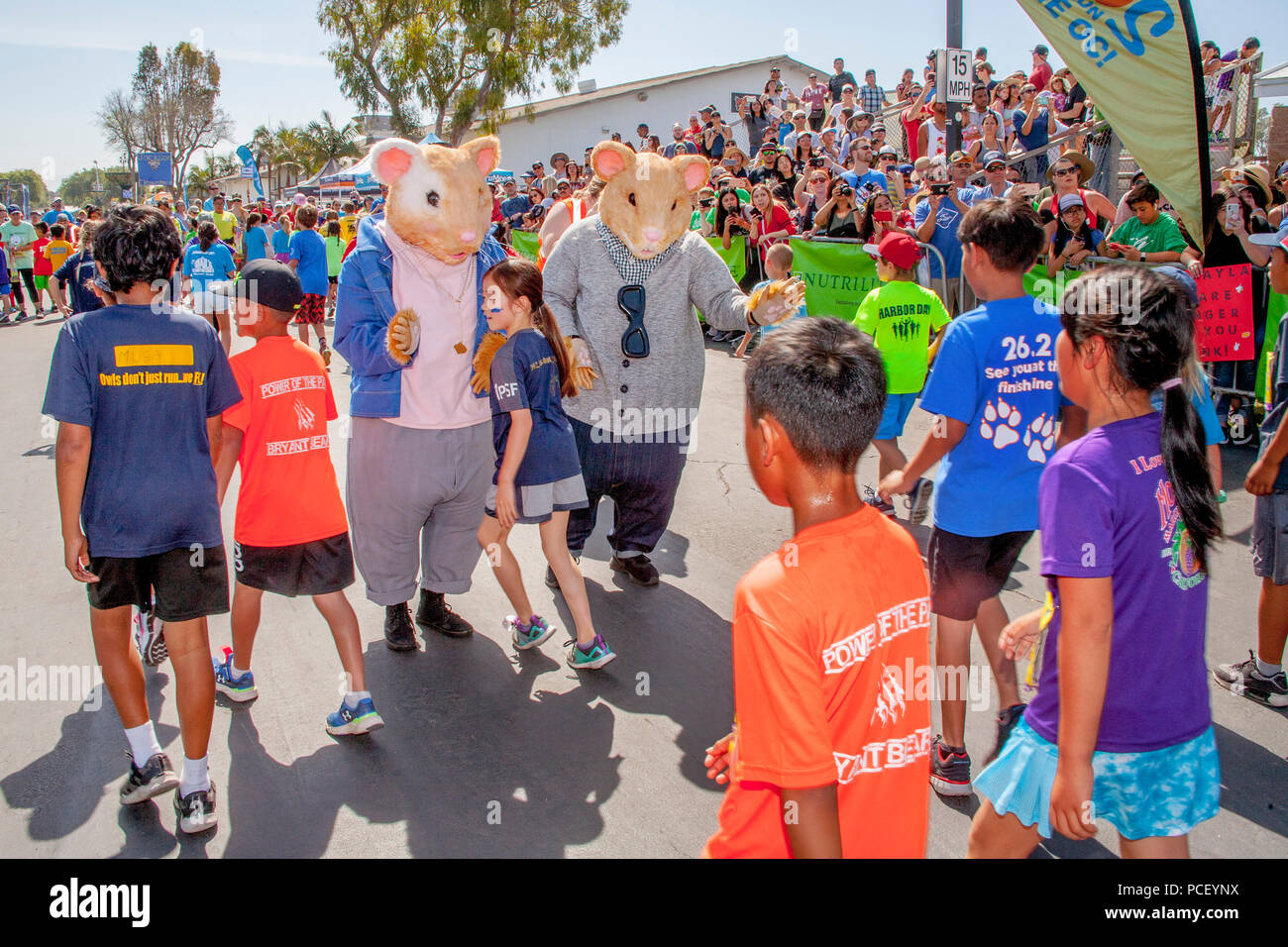 Two greeters in hamster costumes high five child runners at the finish