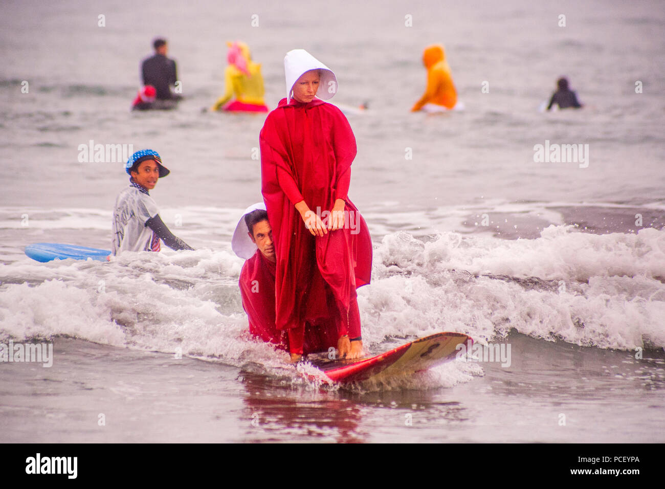 In costumes from 'The Handmaid's Tale,' two surfers join in a Halloween costumed surfing event in Huntington Beach, CA.  (Photo by Spencer Grant) Stock Photo