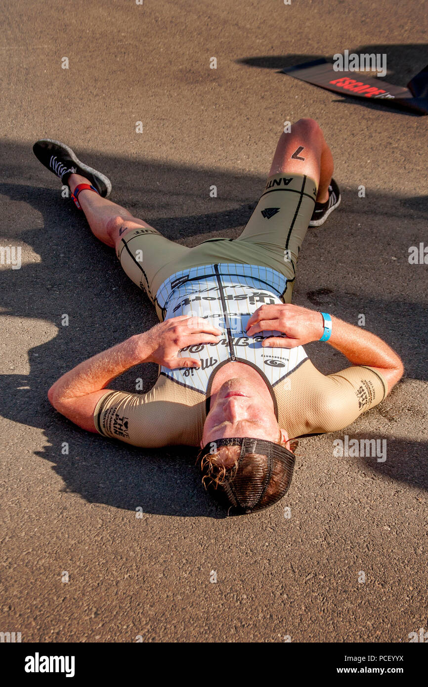 An exhausted third-place triathlon winner lies down in the shade to catch his breath at the finish line in a Huntington Beach, CA, parking lot.   (Photo by Spencer Grant) Stock Photo