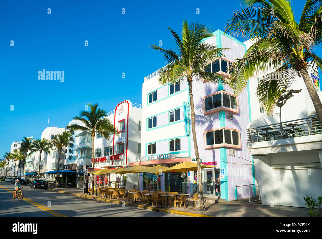 MIAMI - CIRCA JUNE 2018: Restaurants on the tourist strip of Ocean Drive stand ready for morning customers in South Beaches as a cyclist rides by. Stock Photo