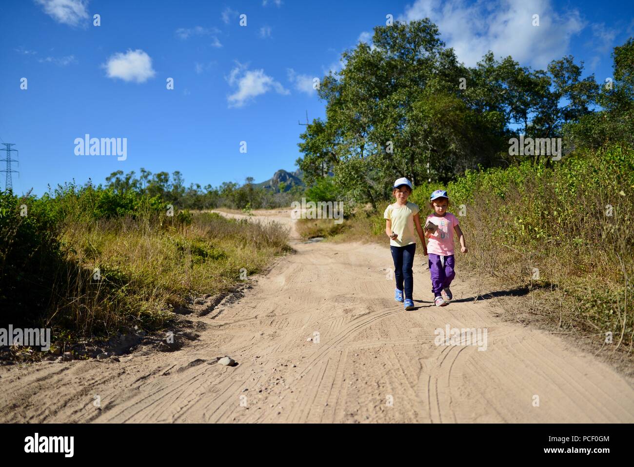 Two children walk down a dry dusty dirt road, Townsville, Queensland ...