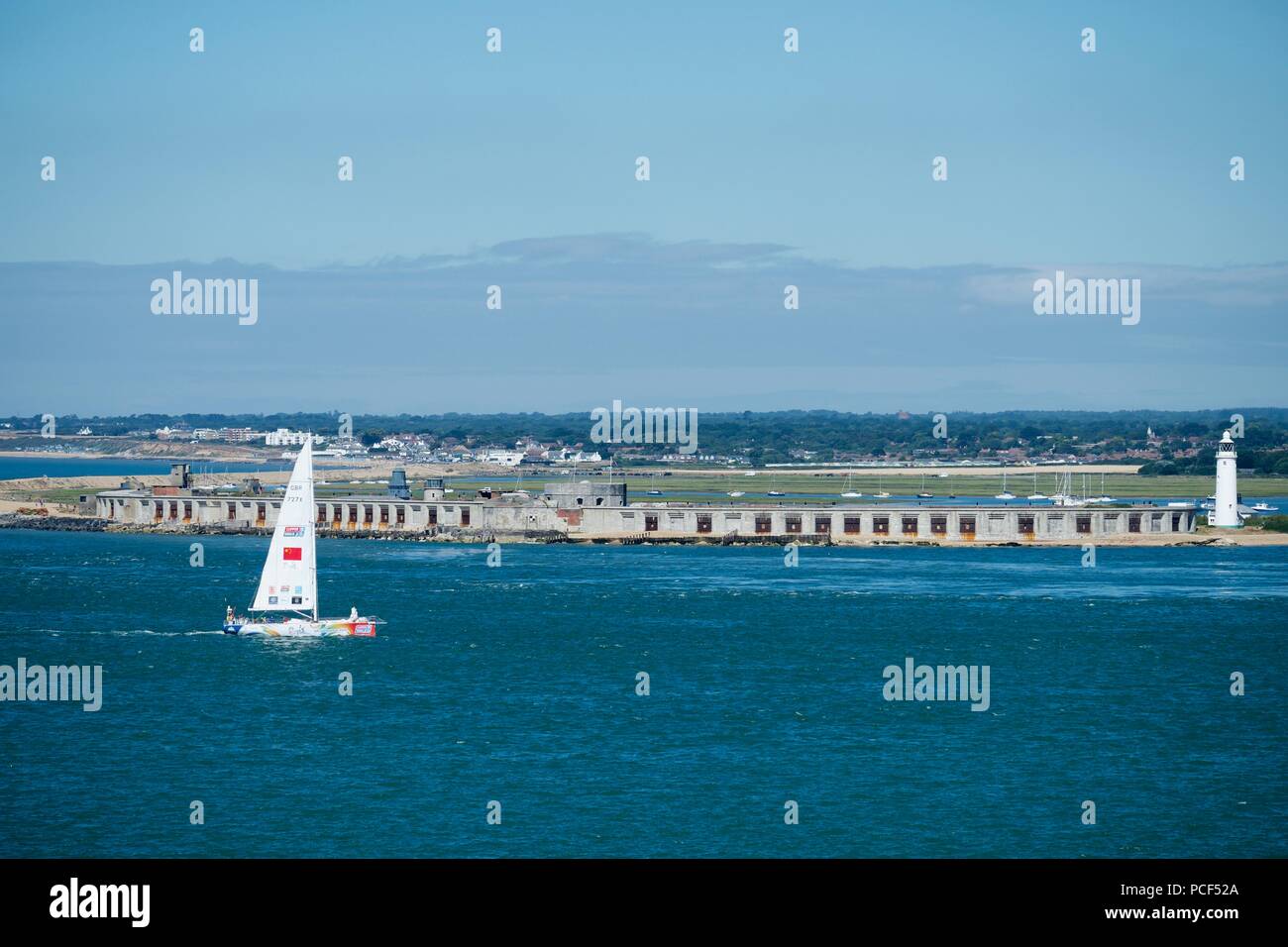 racing boat in the Solent sailing past Hurst Castle and lighthouse Stock Photo