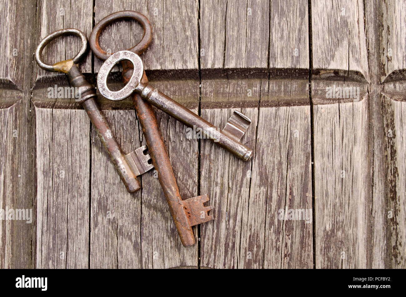 Vintage keys on old wooden background. Close-up. Three old, rustic keys on the table. Stock Photo